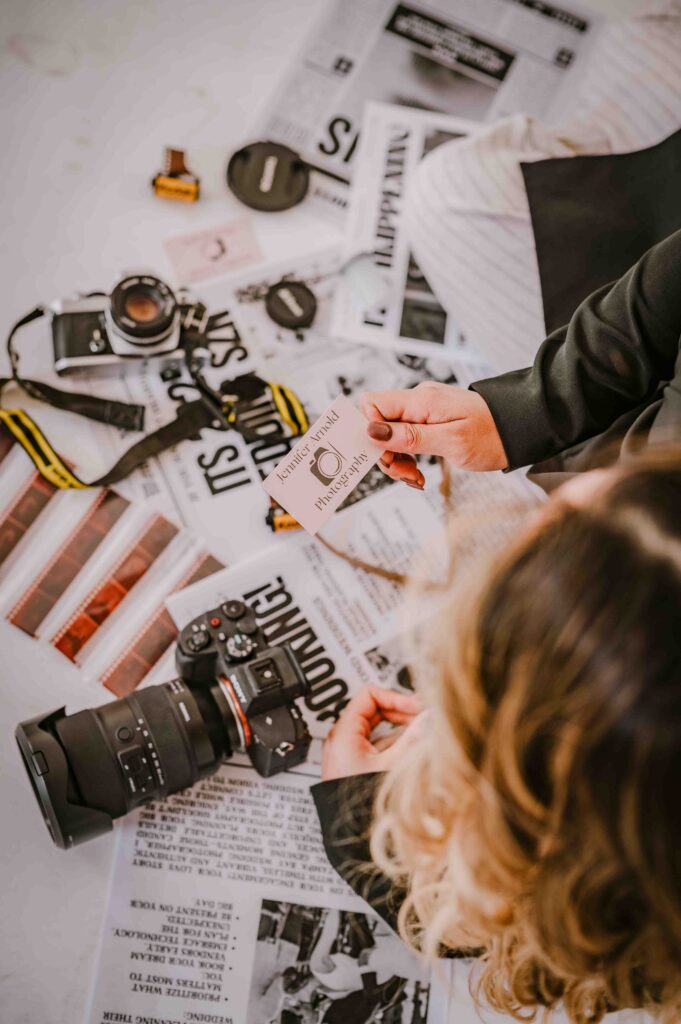 newspapers and person holding business card for photography business