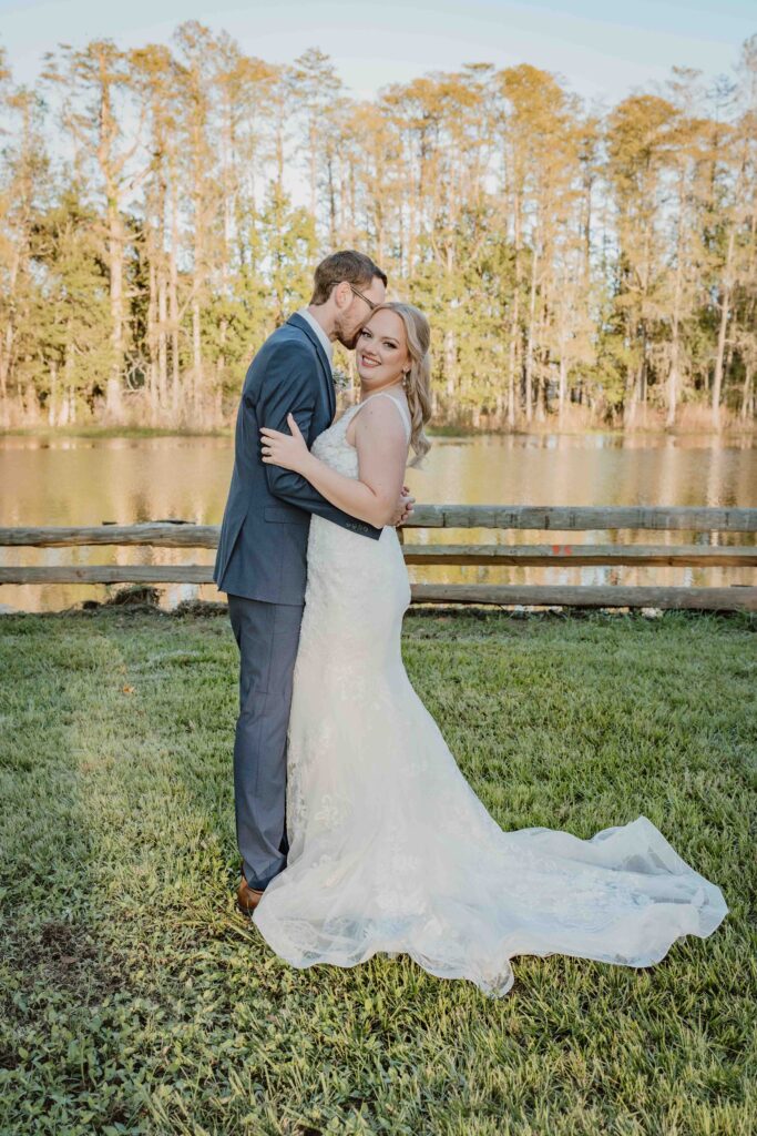 bride and groom kissing in front of a lake