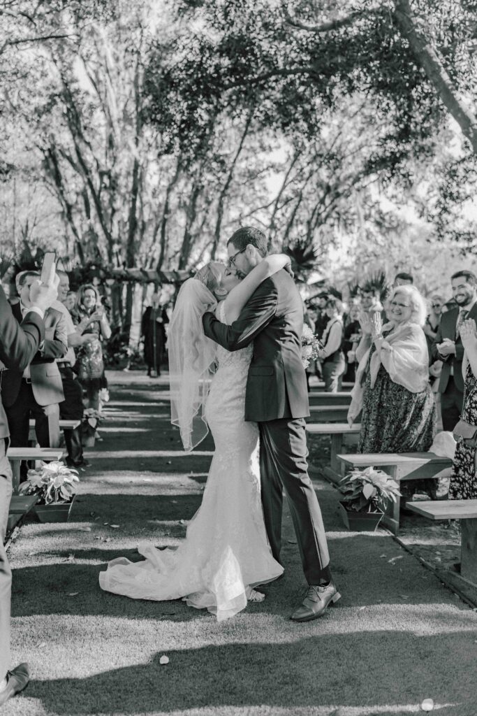 black and white photo of bride and groom kissing during the ceremony