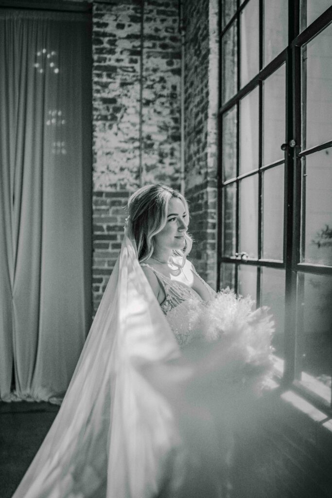 black and white picture of a bride looking out the window 
