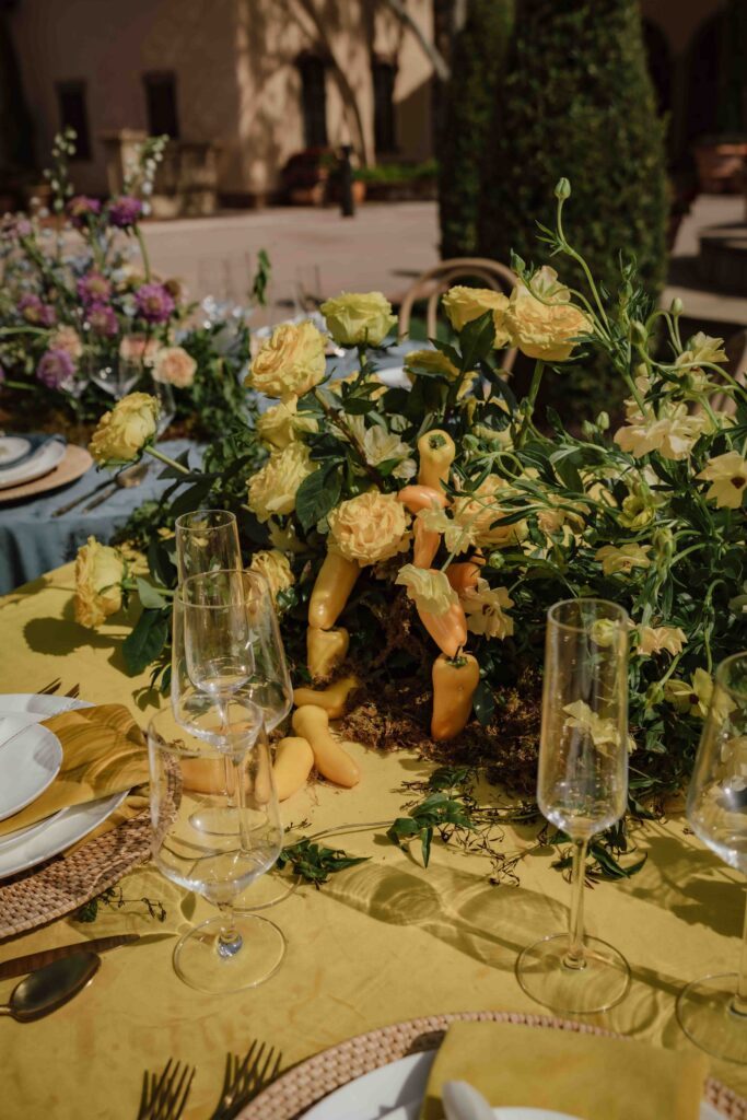 yellow tablescape with plates, glasses, yellow flowers and yellow peppers