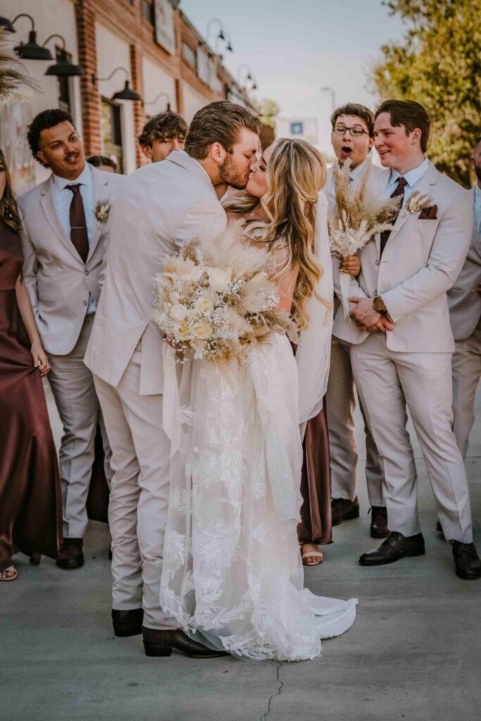 Couple kissing in front of a wedding party cheering them on