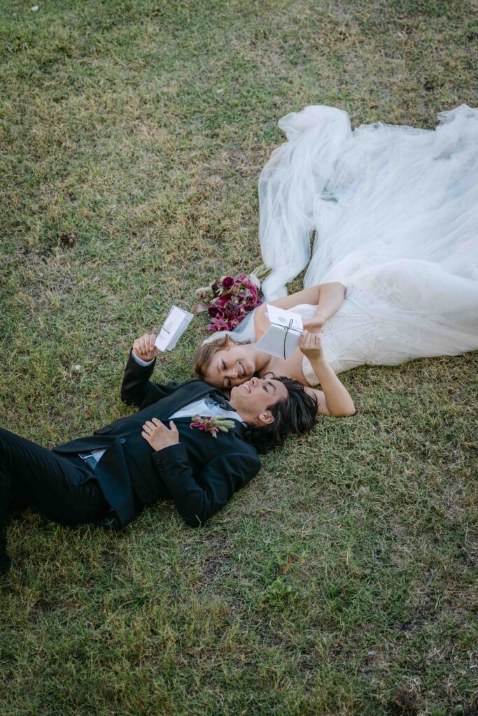 couple laying on the grass reading vows to each other