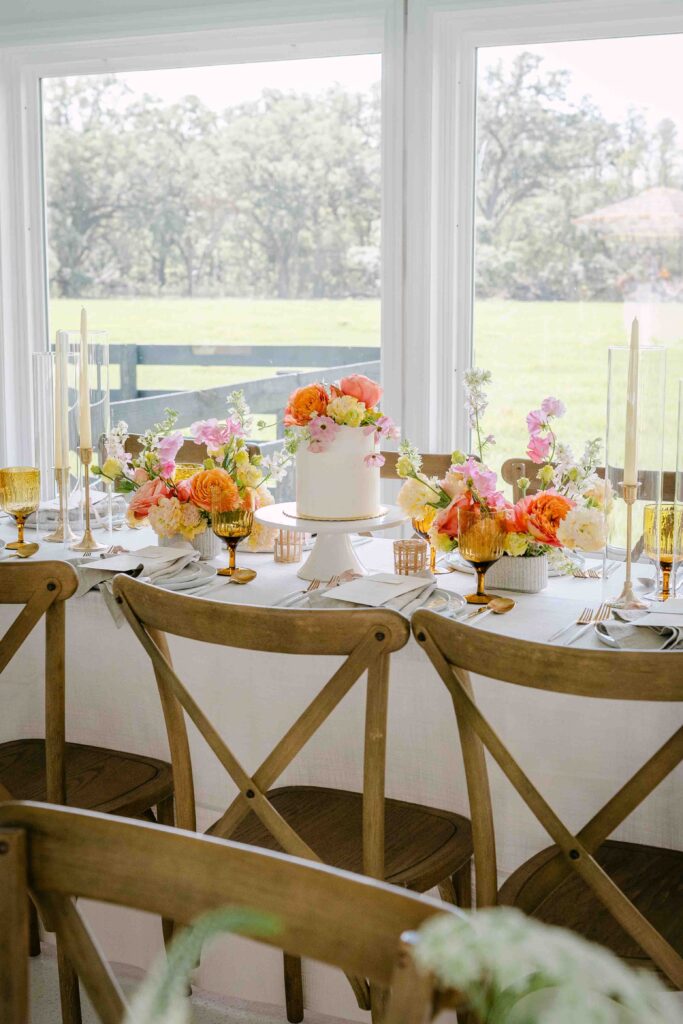 tablescape with candles, orange flowers, and a cake centerpiece