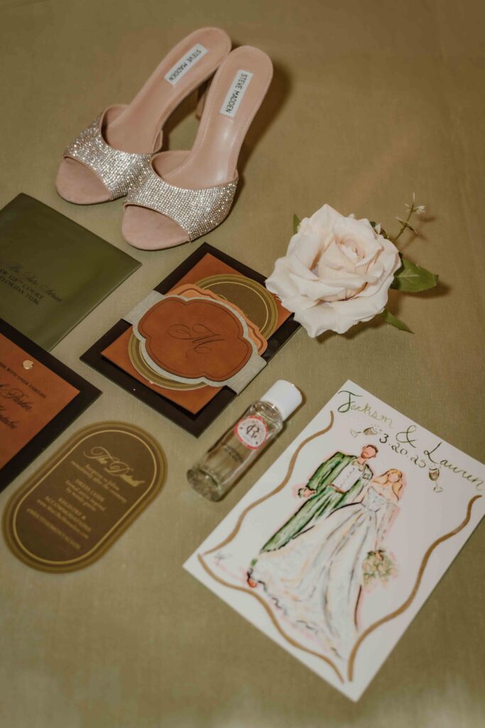 flat lay of invitation, painting, shoes, and flowers