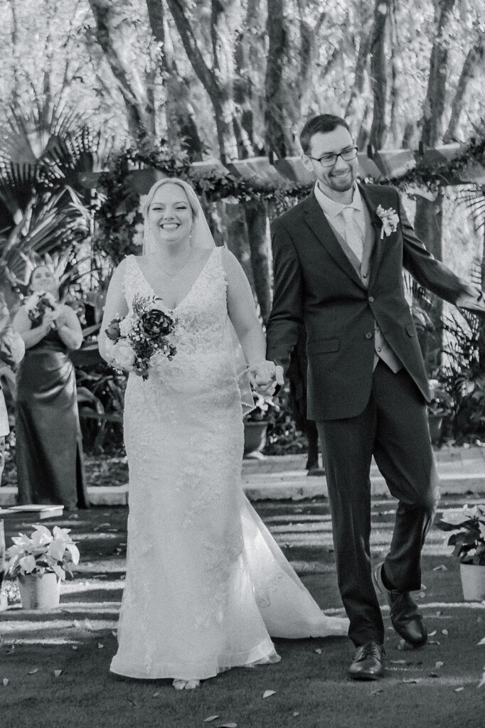 black and white phot of bride and groom walking away after first kiss during the wedding ceremony