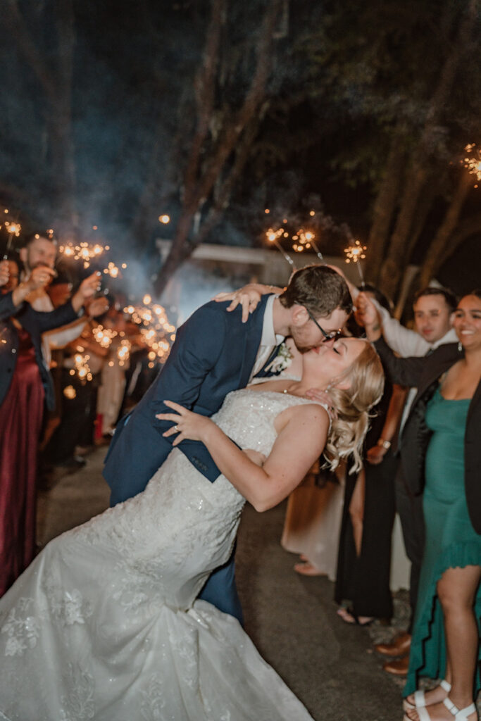 bride and groom kissing with sparkler exit in the background