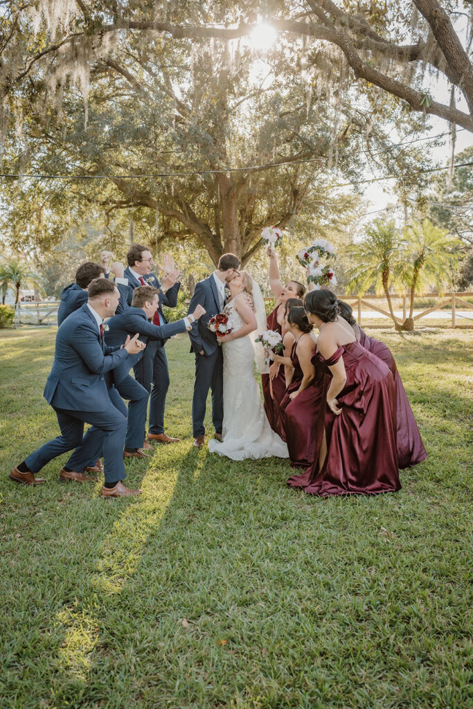 wedding party cheering on bride and groom kissing