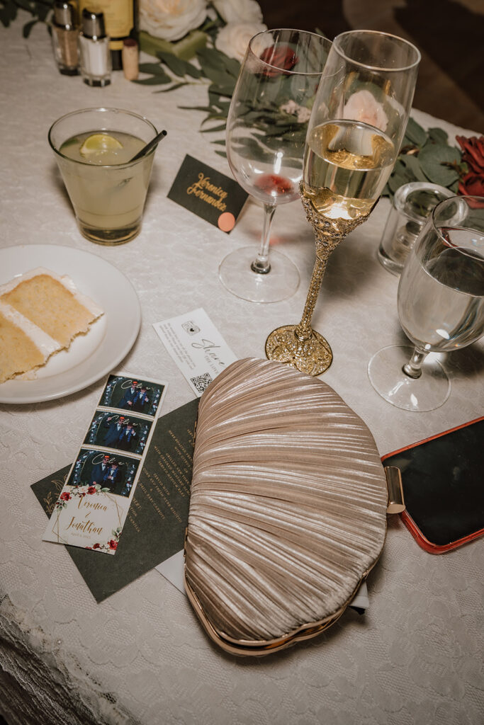 sweetheart table close up of cake, champagne, photobooth photo, purse, and phone