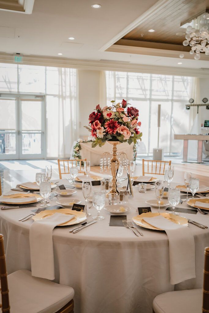 wedding dinner table setting with plates and red flowers