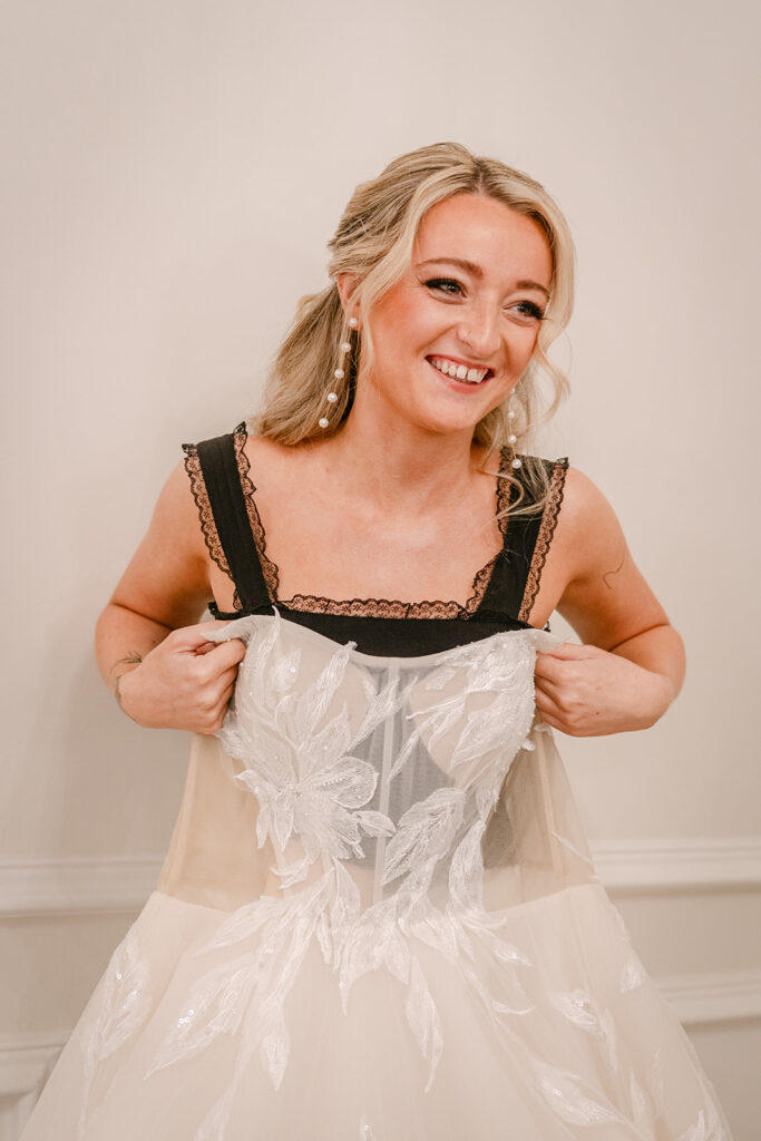 bride holding up wedding dress and smiling