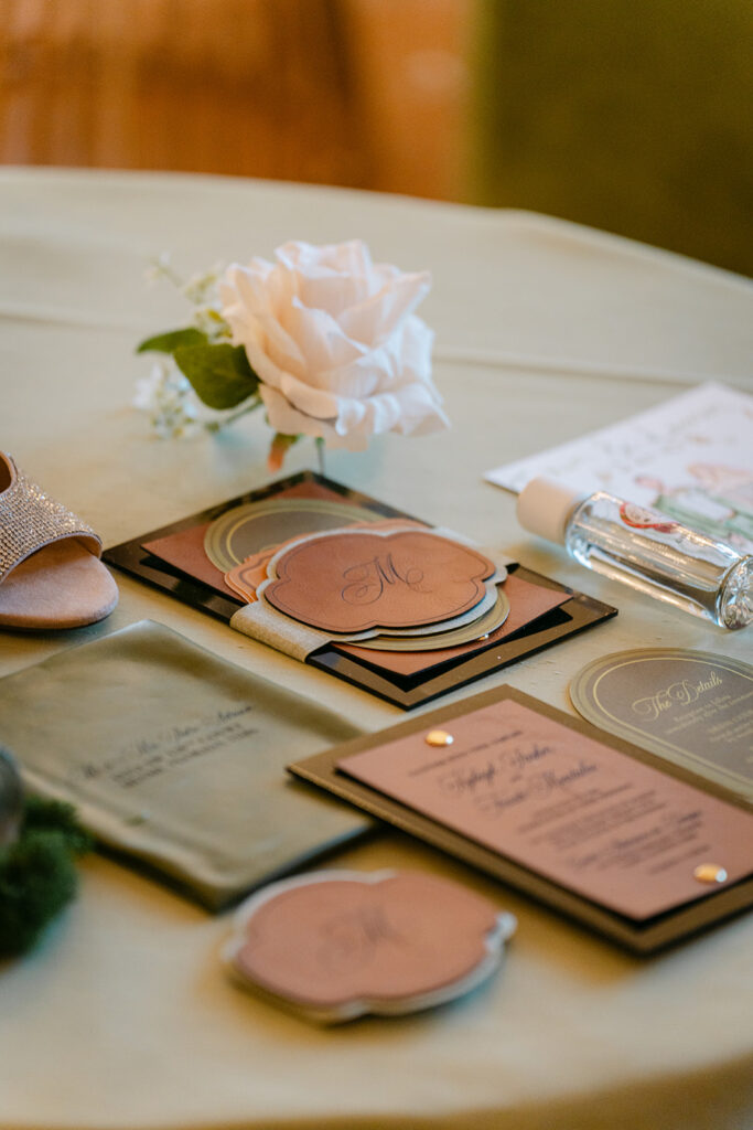 green flat lay with leather invitation and perfume