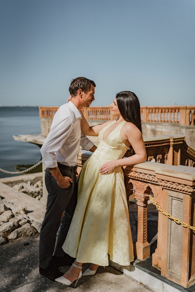 man and woman facing each other leaning against a railing