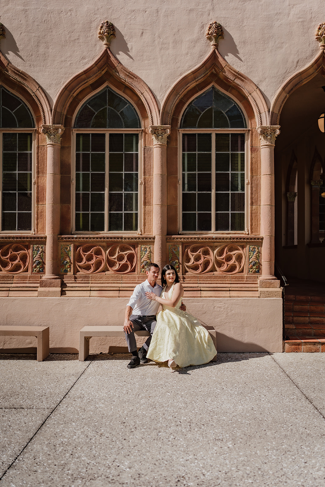 man and woman facing the camera sitting in front of a museum