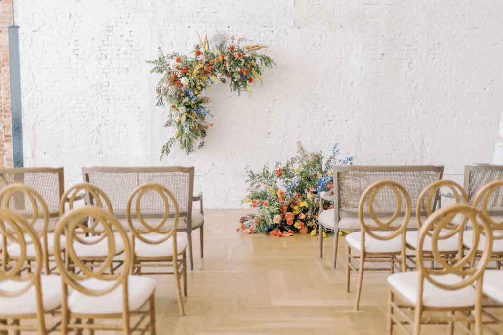 ballroom with a floral ceremony centerpiece and wooden ceremony chairs