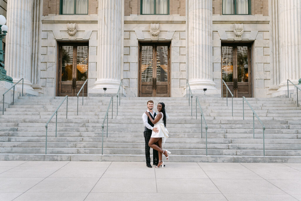 man and woman looking at the camera smiling in front of the courthouse