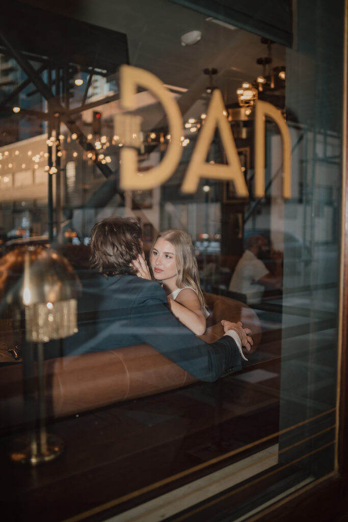 man and woman looking at each other with a hand around his neck through the window