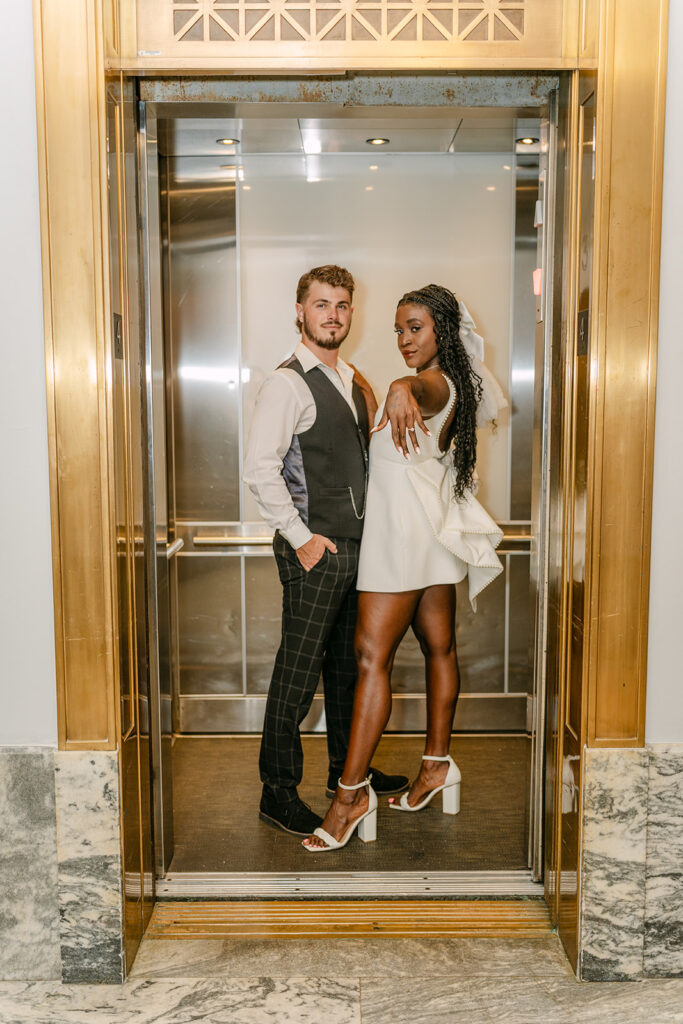 man and woman in elevator with woman showing off her engagement ring